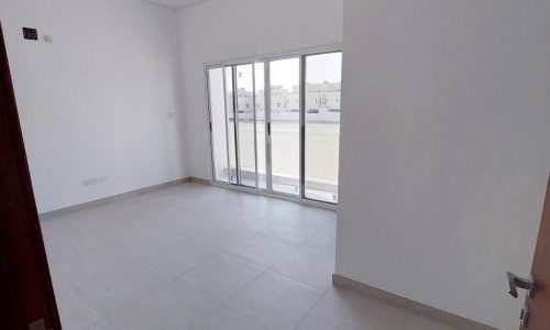 An empty room with sliding glass doors and a balcony, located in Durrat Al Muharraq.
