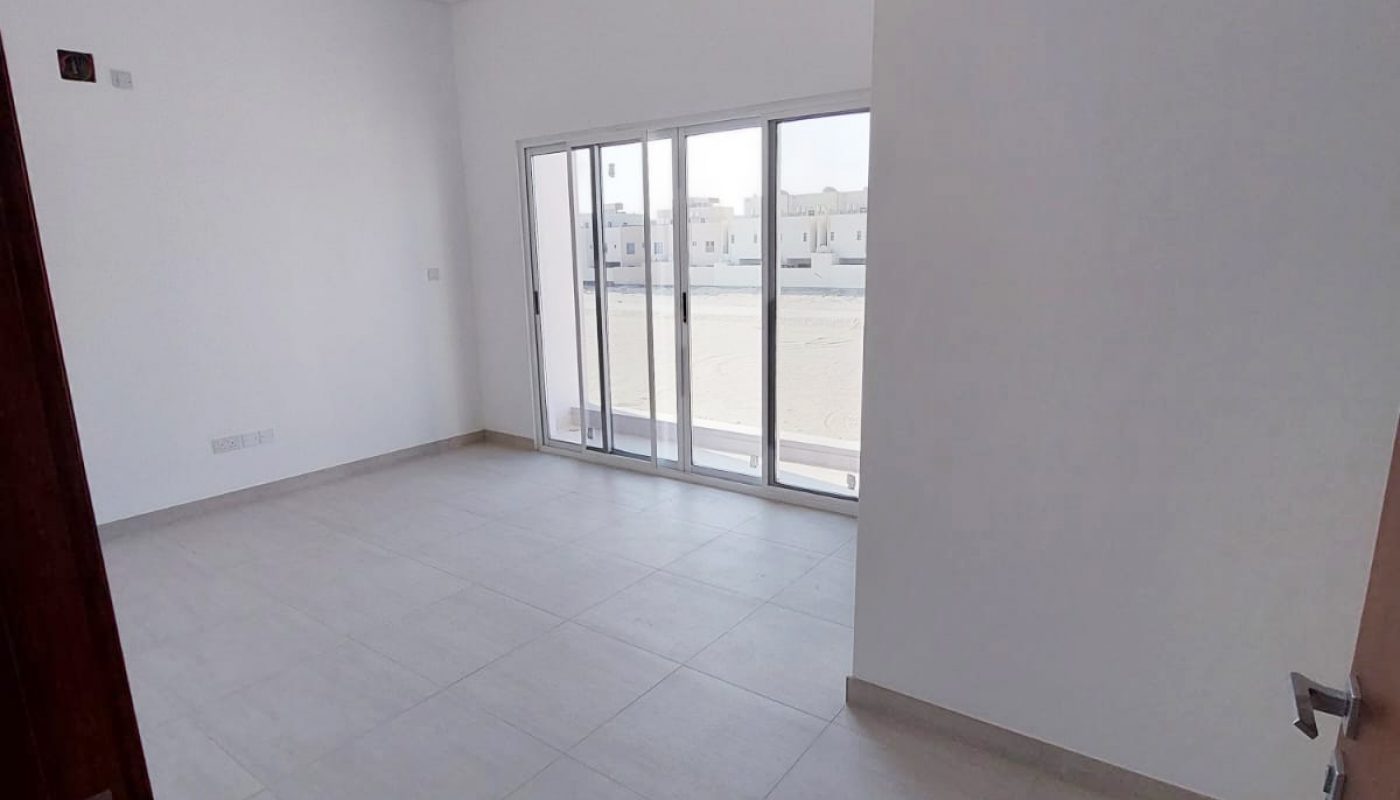 An empty room with sliding glass doors and a balcony, located in Durrat Al Muharraq.