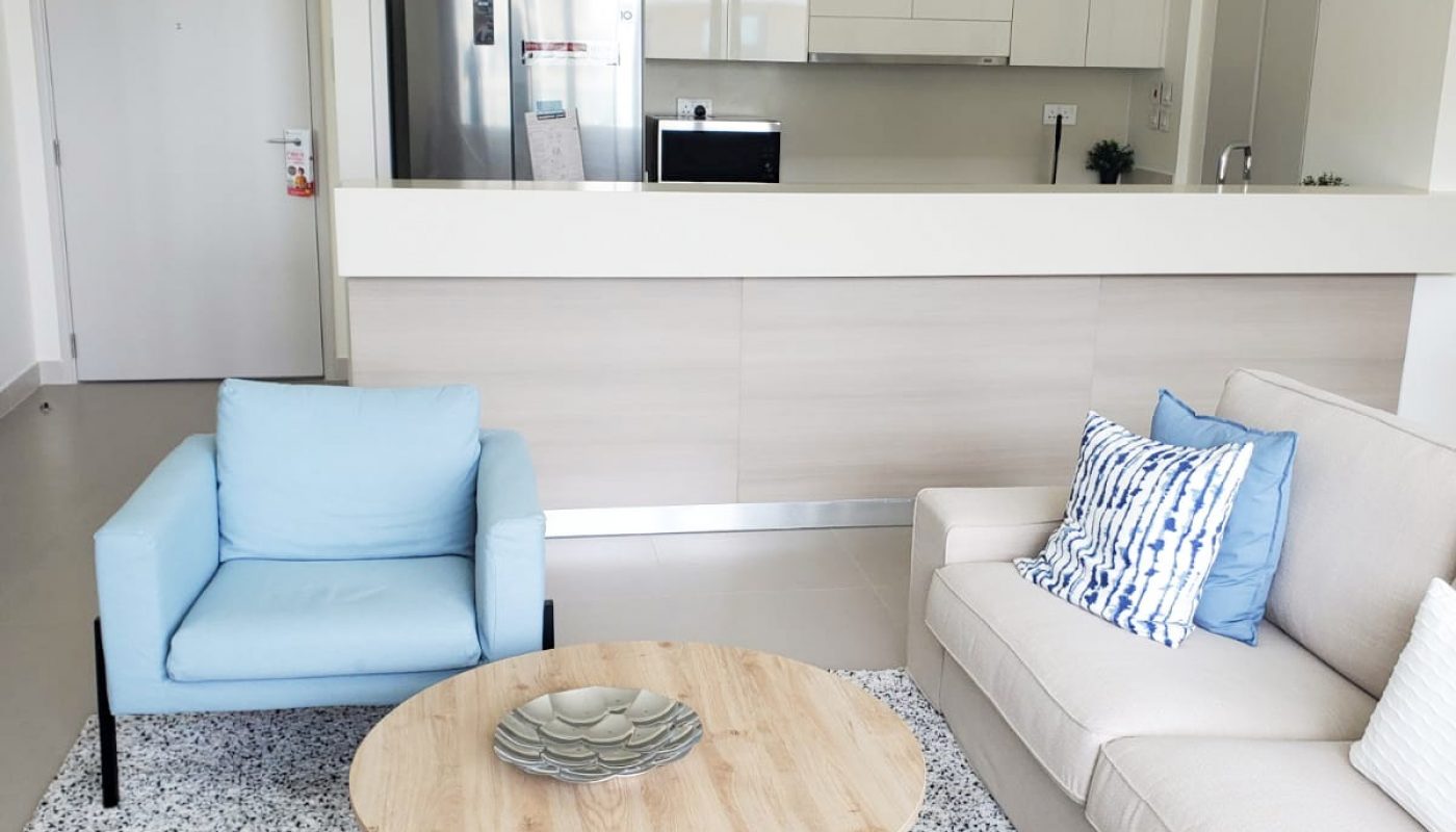 A Marassi apartment with blue couches and a coffee table available for rent in the living room.