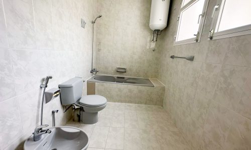 A spacious villa for rent with a bathroom featuring a toilet, sink, and tub.