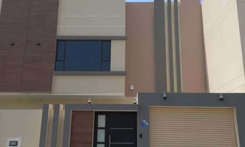 A mesmerizing two-story house with two garages and a garage door.