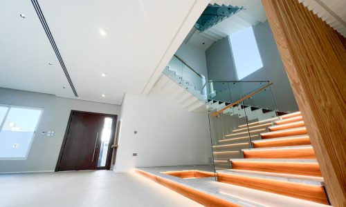 A luxurious house with a modern staircase featuring wooden railings.