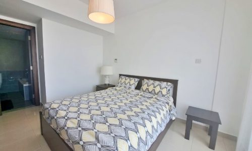 An apartment bedroom with a bed and a bedside table.