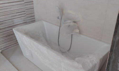 A white bathtub in a bathroom with tiled walls in a mesmerising villa for sale.