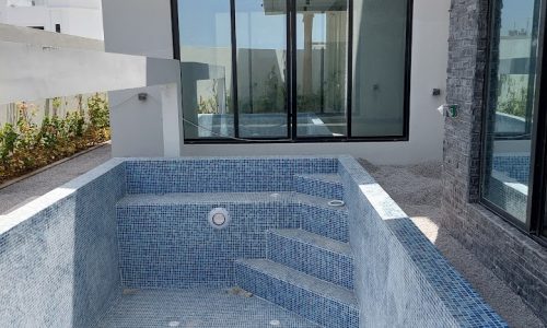 Mesmerising blue tiled swimming pool in front of a house for sale in Al Qurrayah.