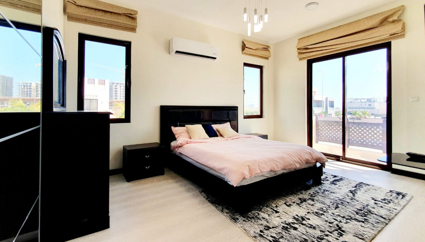Modern bedroom with a double bed, two nightstands, a patterned rug, dresser, and large windows with beige shades letting in natural light.