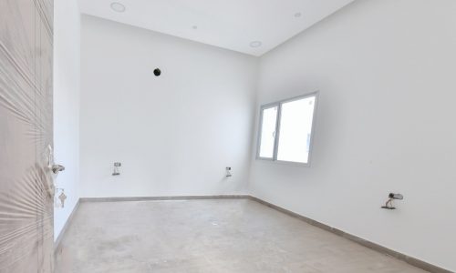 An empty room with white walls and a door in a brand new villa.