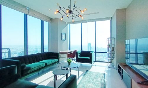 A luxurious apartment in Seef available for rent, featuring a spacious living room with large windows overlooking the city.