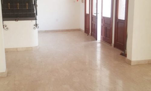 A spacious villa in Busaiteen available for rent. The villa offers a large empty room with marble floors and a ceiling fan for comfortable living.