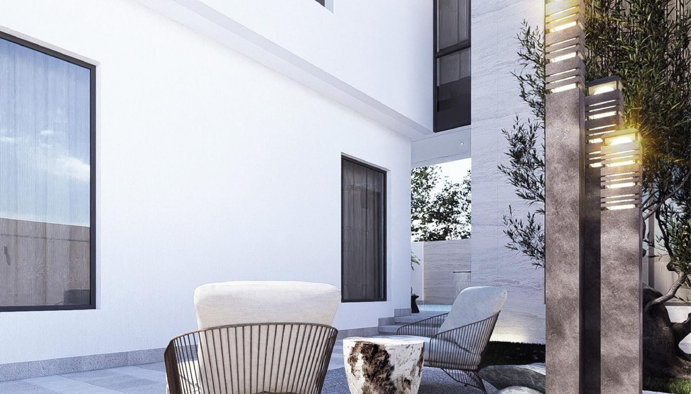 Modern outdoor patio with minimalist chairs, a small round table, stone accents, and tall light fixtures beside a white building with large windows.