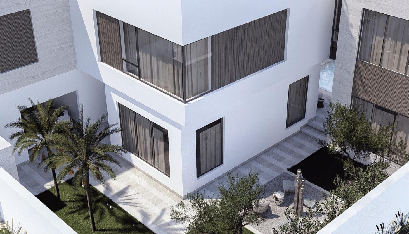 Modern white two-story house with large windows, a fenced yard, palm trees, green lawn, and a small patio area with seating.