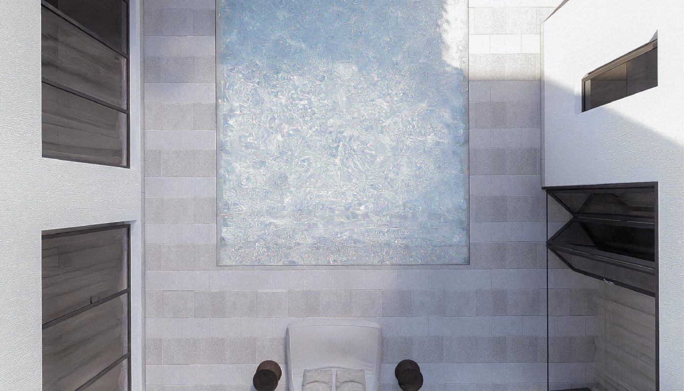 Aerial view of a rectangular pool with water cascading from above, surrounded by white walls, glass doors, two small tables, and a single lounge chair.