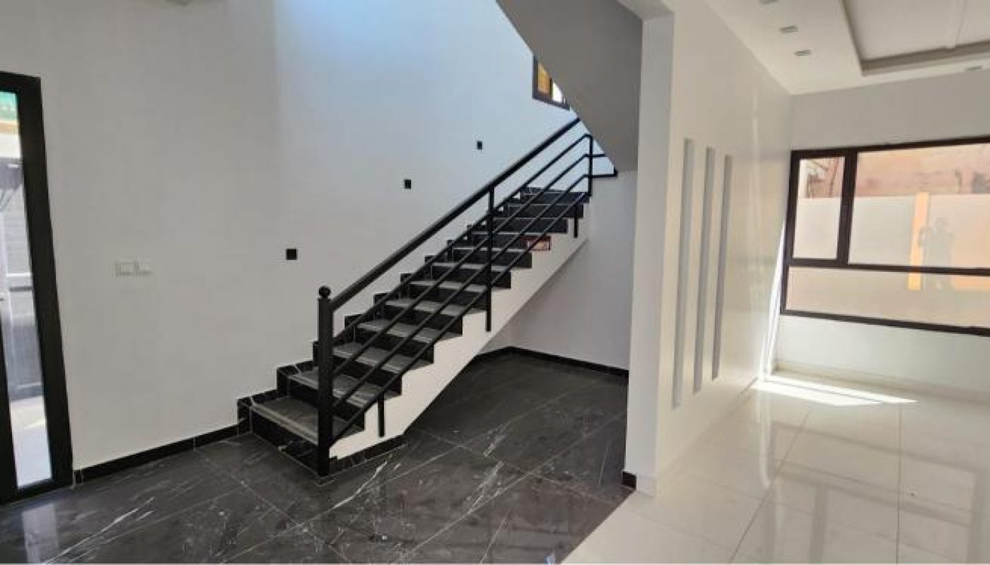 A modern interior with black-tiled stairs, black-and-white flooring, and large windows allowing natural light into the open space.