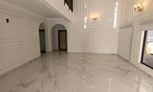 A spacious room with a white marble floor.