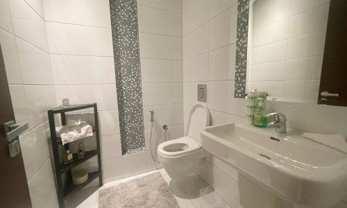 A clean and modern bathroom interior with a toilet, sink, decorative mosaic tiles, and Auto Draft.