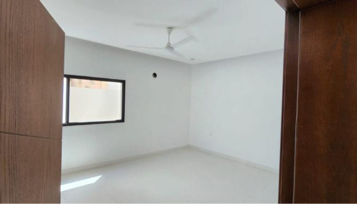Empty white room with a ceiling fan, window, and wooden door partially open in the foreground.
