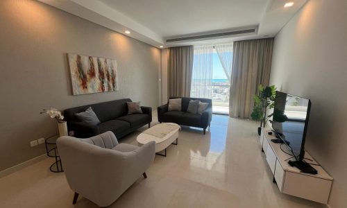 A living room with furniture and a view of the ocean.