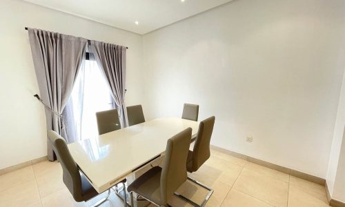 A stunning dining room with a white table and chairs in an apartment for rent, offering 24/7 security in Busaiteen.