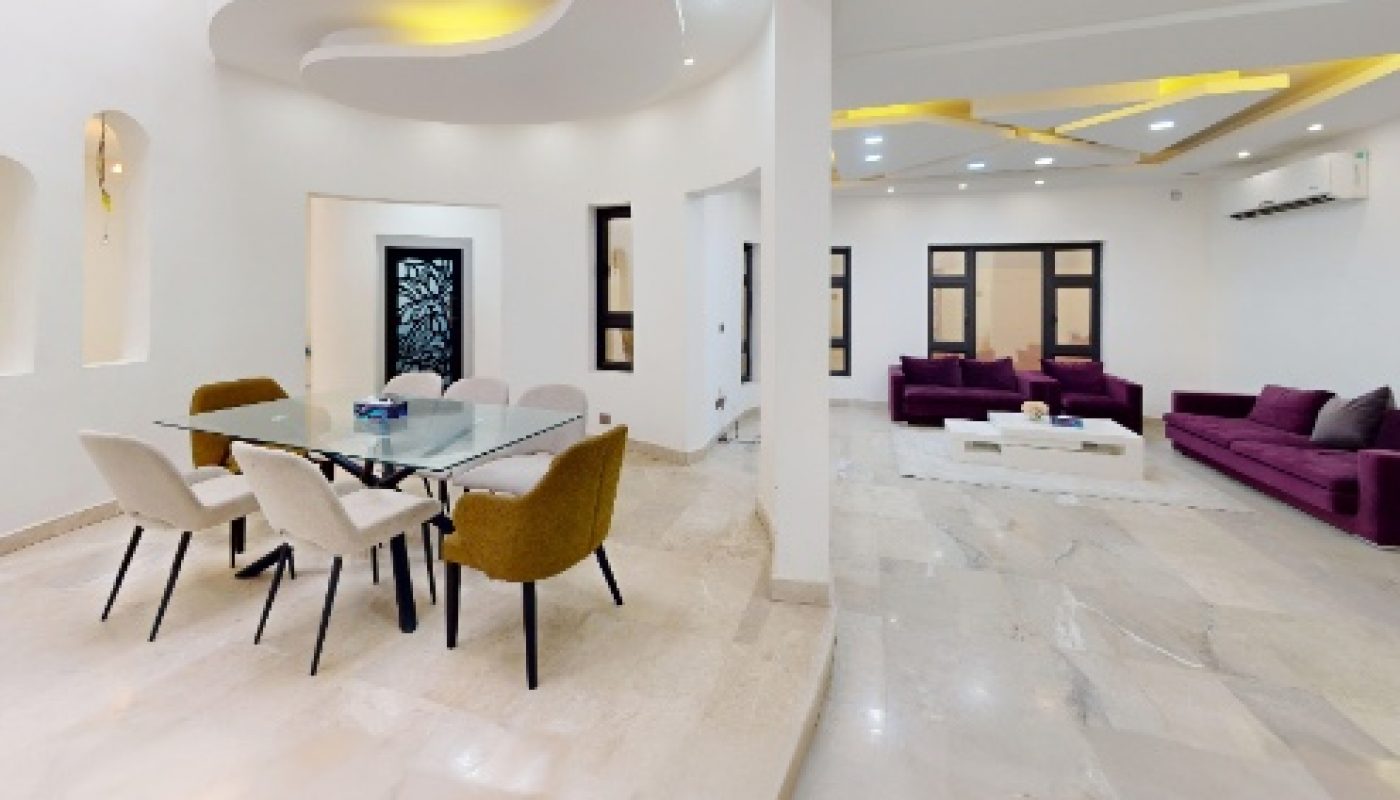 Modern open-concept living and dining area with marble floors, white walls, contemporary furniture, and recessed ceiling lighting.