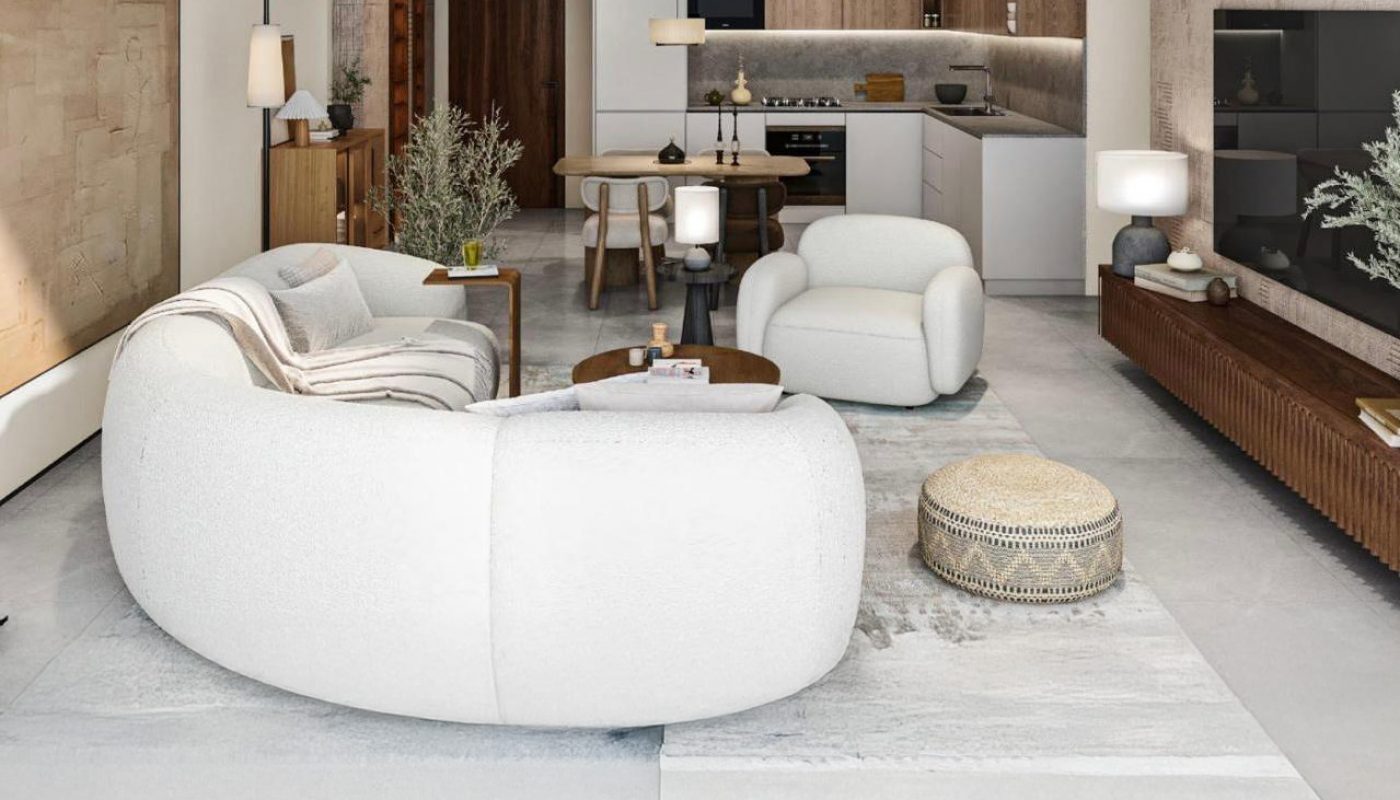 Modern open-plan living room and kitchen with neutral tones, curved white sofas, a round coffee table, and minimalistic decor.