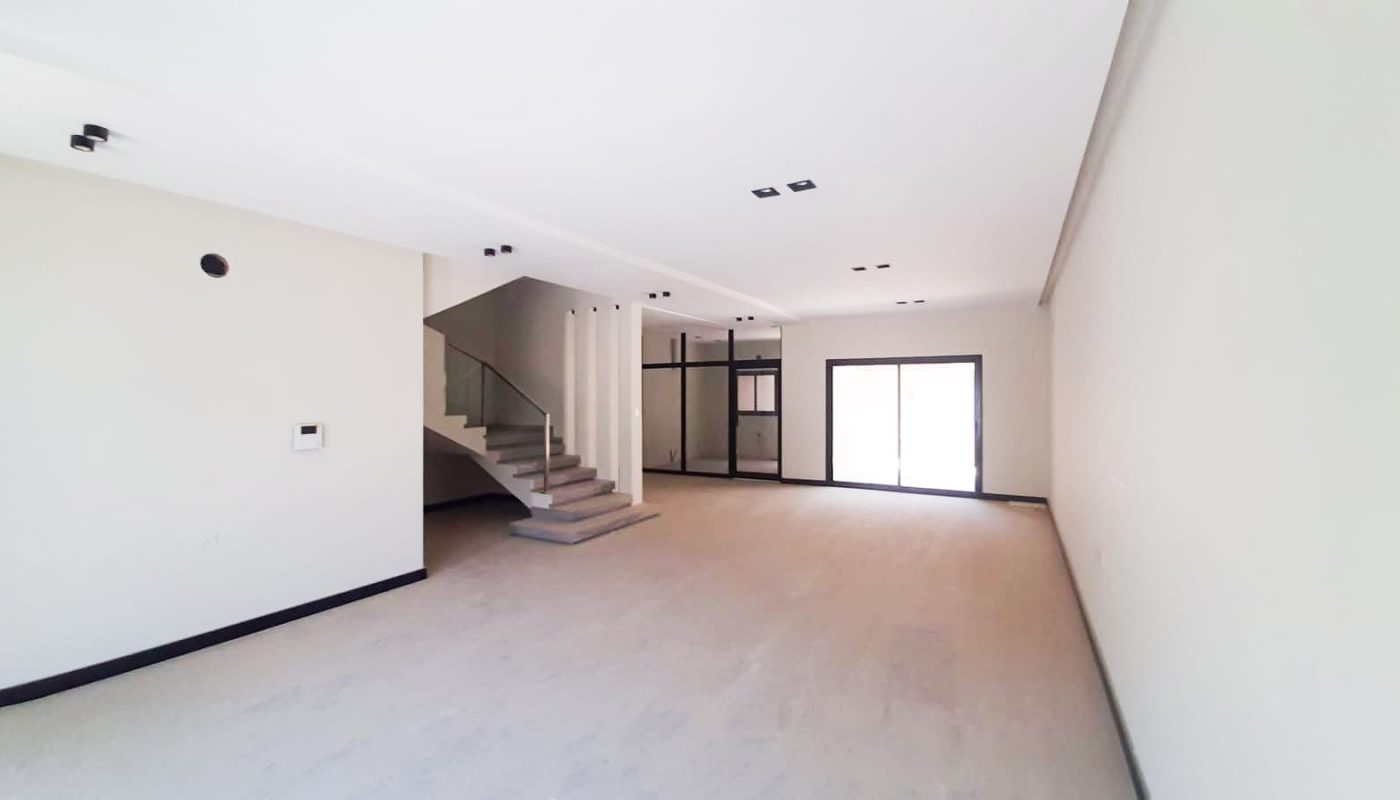Luxury 3 Bedrooms Villa for Sale in Durrat Al Muharraq featuring a large empty room with stairs and white walls.