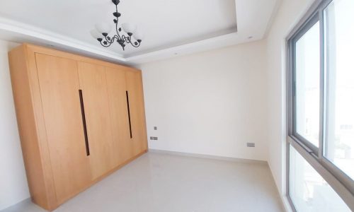 An empty apartment with wooden cupboards and a sea view window available for rent.