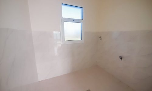 A bright bathroom with white walls and a window.