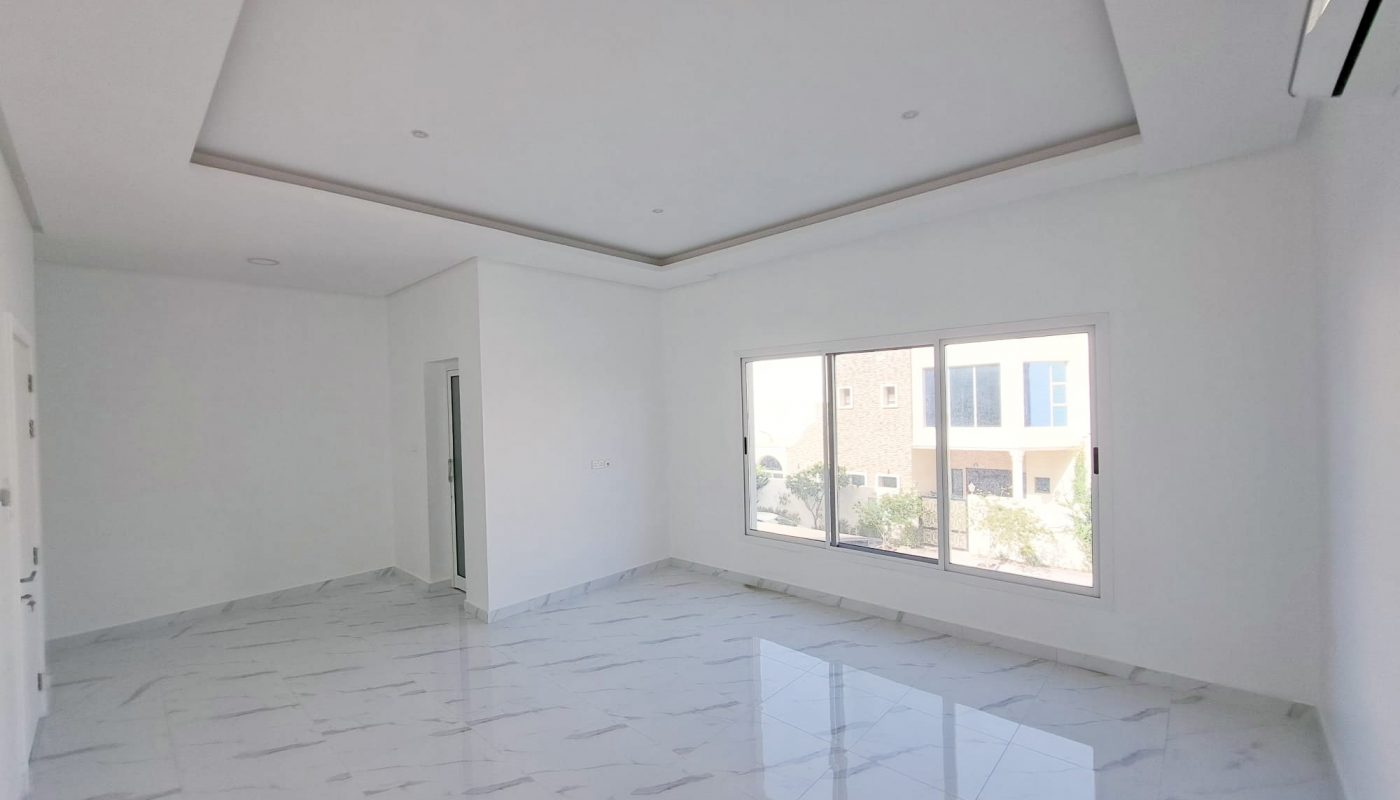 A luxurious 4BR Villa in Al Shakhura with an empty room featuring white walls and tile floors.