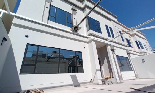 A white house with windows and a balcony, located in Bani Jamra, for sale.