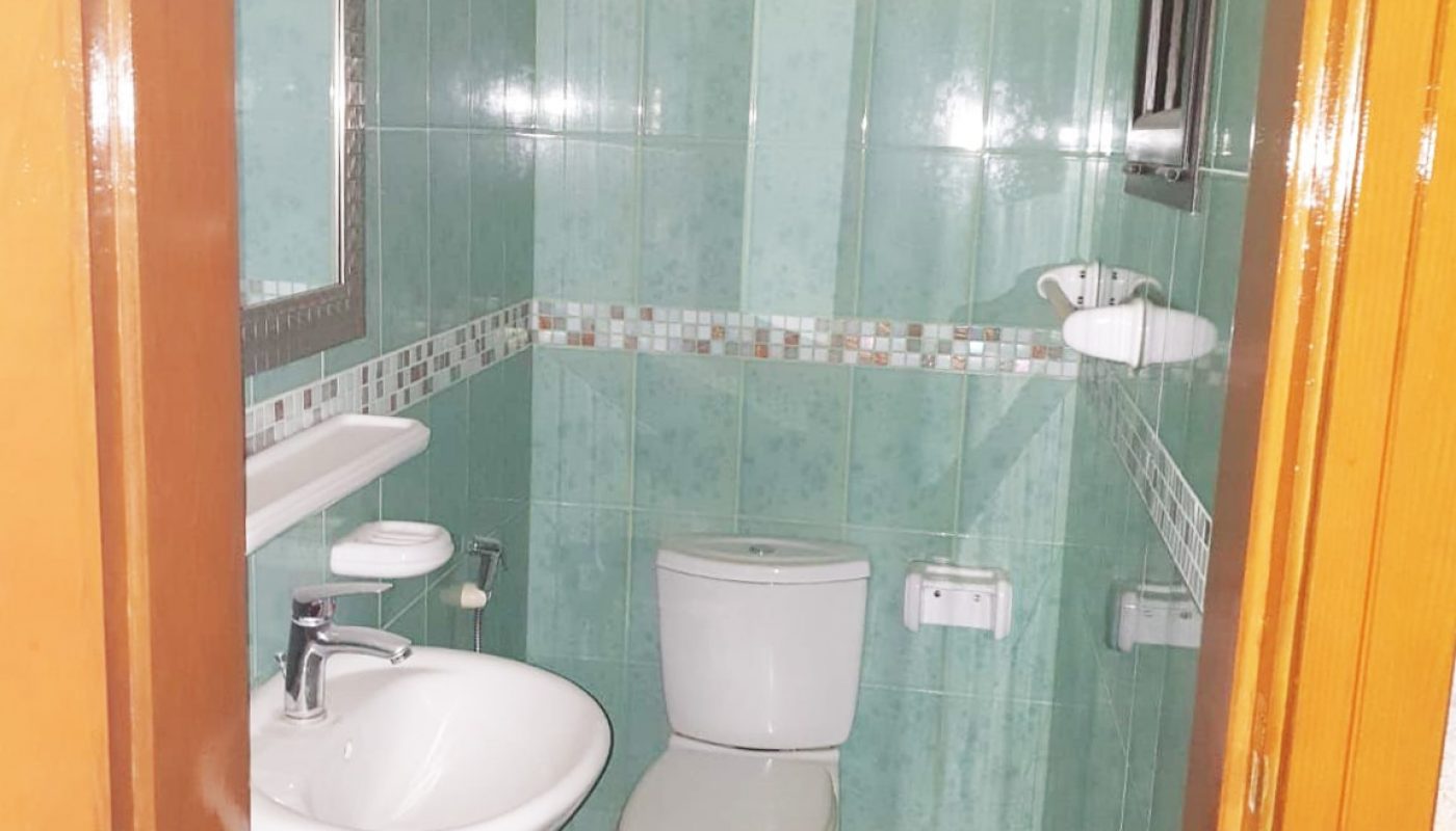 A cozy 2BR apartment for sale in Busaiteen with green tiled walls and a toilet.