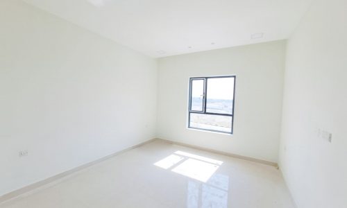 4BR Villa for Sale in Malkiyah with a mesmerizing view of an empty room with white walls and a window.