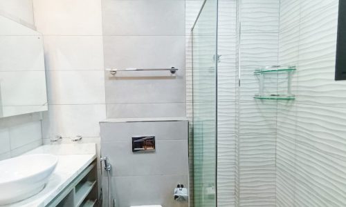 An apartment bathroom with a glass shower and toilet.