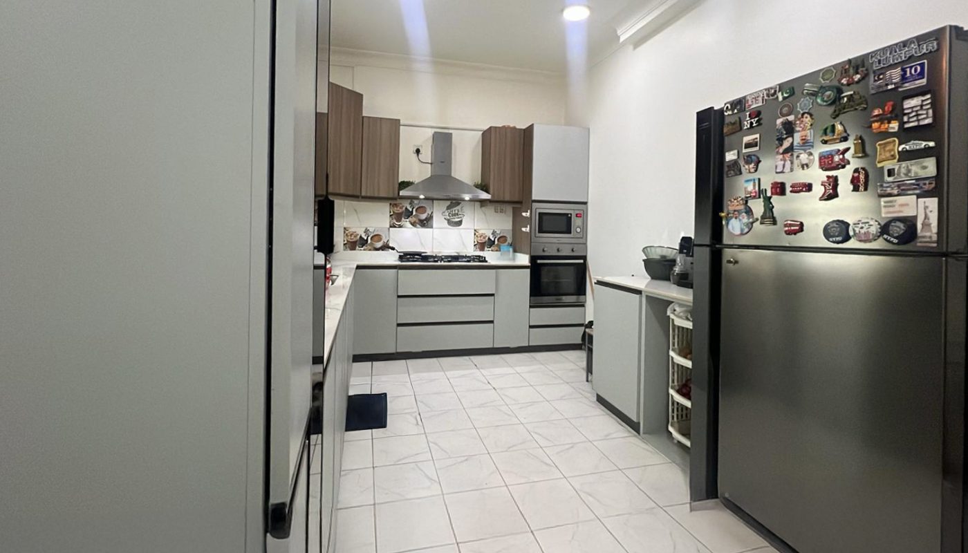Modern kitchen with white cabinets, stainless steel appliances, tiled floor, and a refrigerator covered in magnets. Bright overhead lighting and minimalist decor.