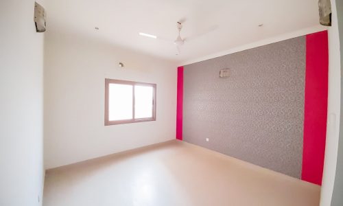 A bright flat for rent in Jeblat Habshi with a pink wall and ceiling fan, perfect for prime location seekers.