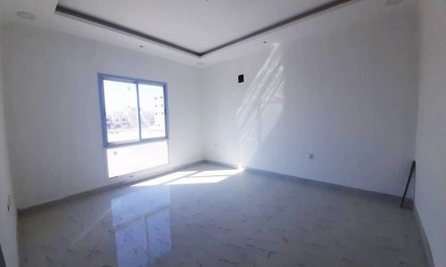 An empty room in a brand new villa with white walls and a window.