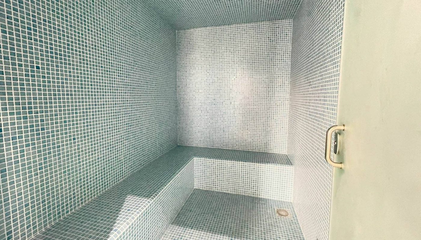 A small bathroom with a blue tiled floor, featuring an automatic ventilation system to prevent drafts.