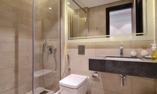 A modern studio for rent in Juffair with a glass shower stall and toilet in a modern building with 24/7 security.