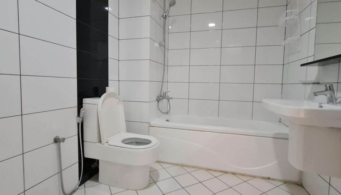 A modern bathroom with white tiled walls and floor, featuring a toilet, wall-mounted sink, and a bathtub with a showerhead.