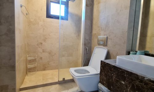 A modern apartment for rent in Juffair with a toilet, sink, and shower.