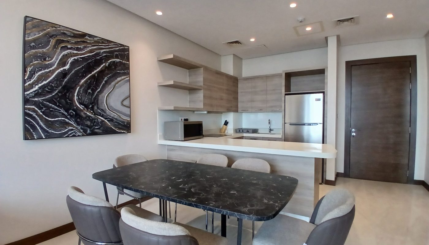 Luxury modern kitchen interior with a marble dining table, grey chairs, abstract art on the wall, and built-in cabinets.