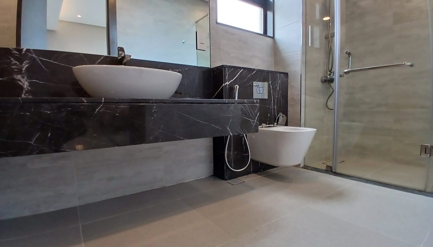 Luxury bathroom featuring a black marble vanity with a white vessel sink, chrome faucet, and a glass-enclosed walk-in shower.