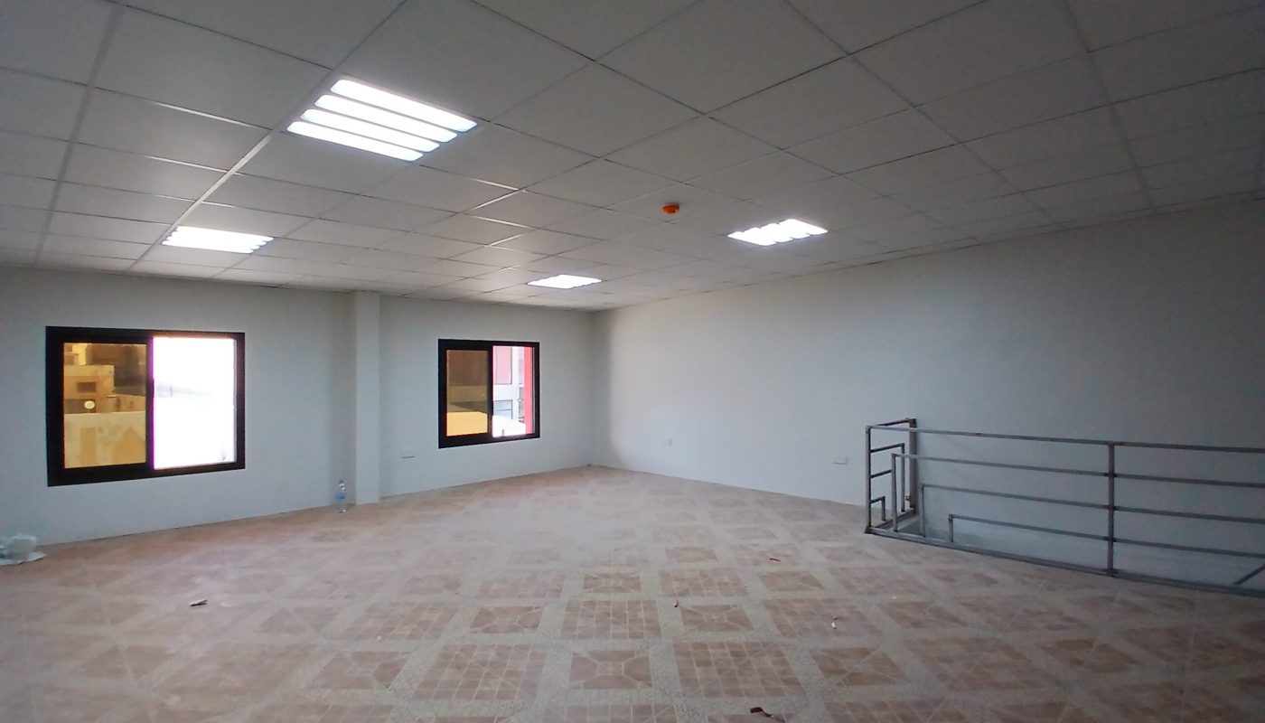 Auto Draft: Empty commercial space with tiled floors, large windows, and fluorescent ceiling lights.