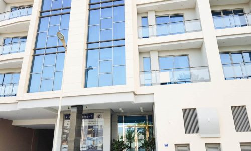 A white car is parked in front of a luxury apartment building on Amwaj Island.