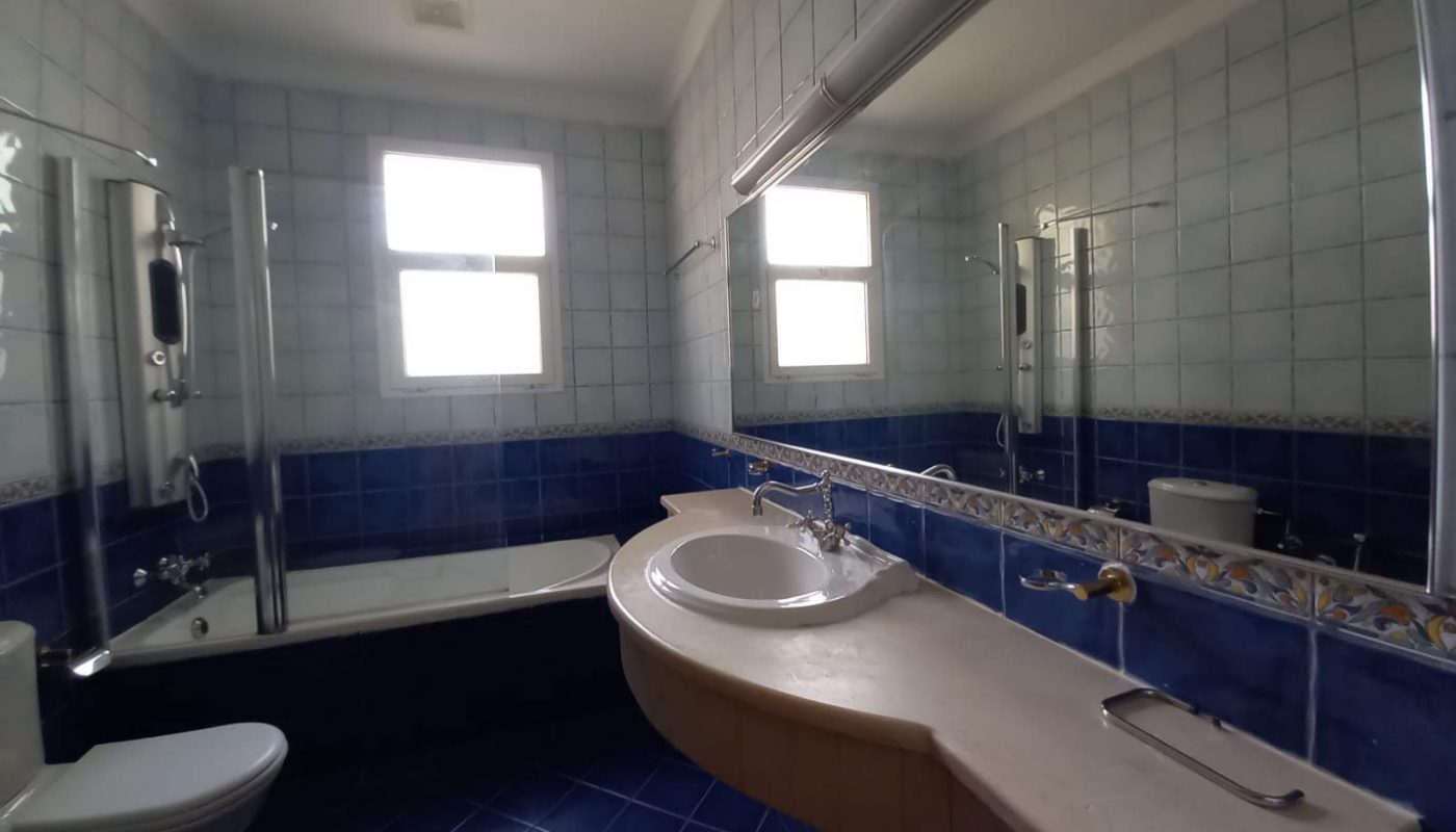 A blue tiled bathroom with a sink and toilet.
