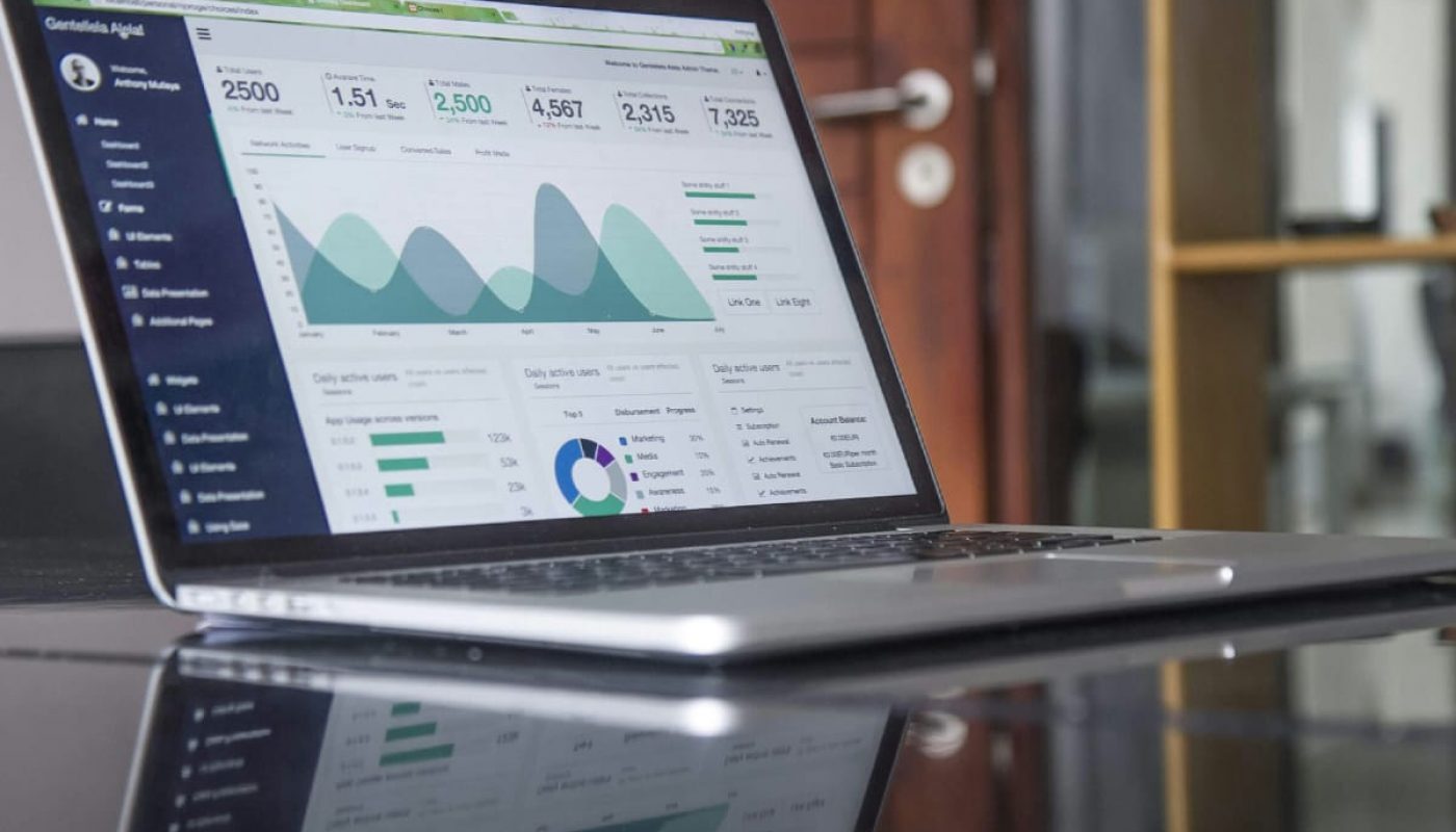 Laptop on a desk displaying the history of real estate analytics data with reflection on a glass surface.