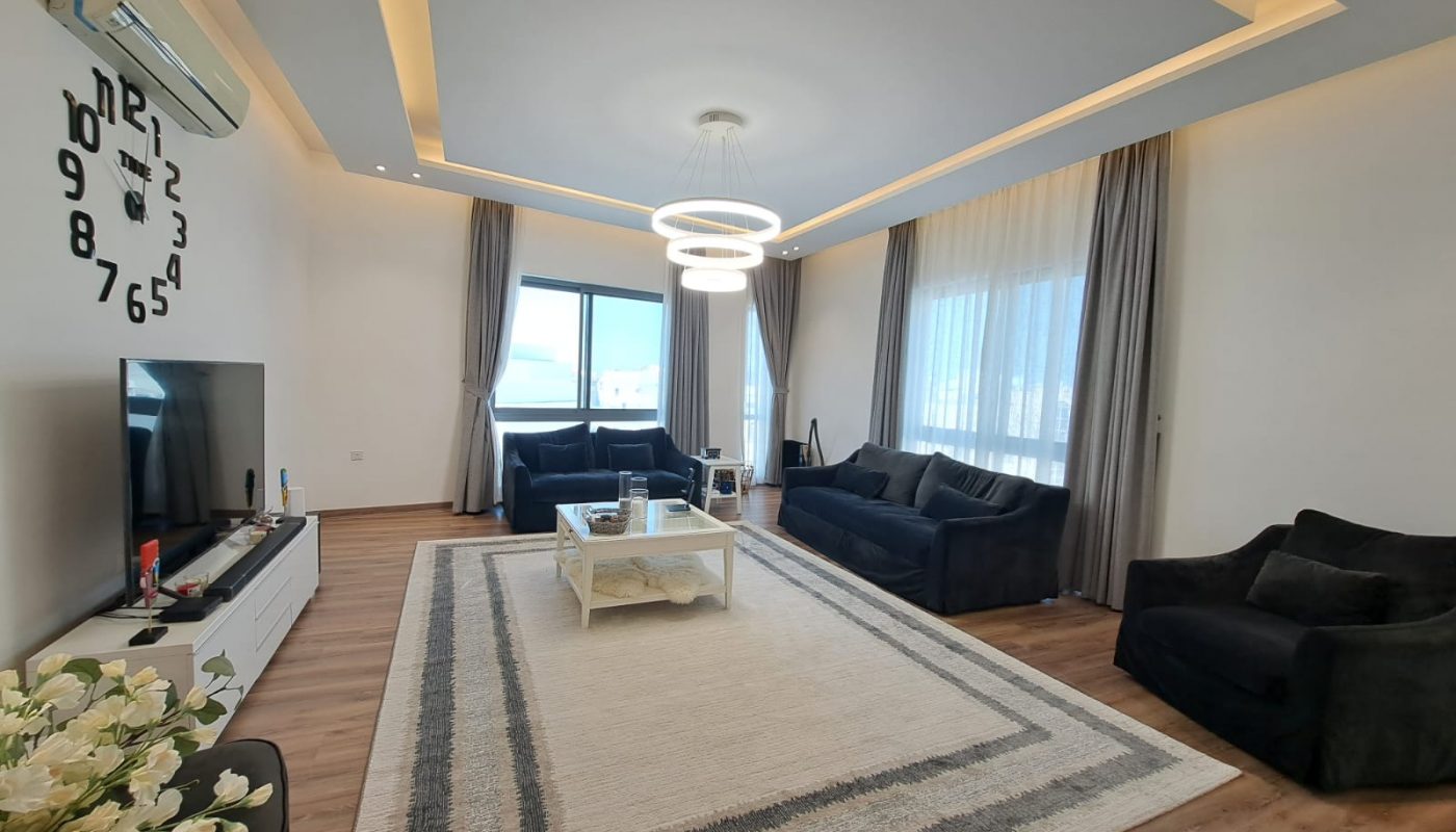 A luxurious apartment in Al Janabiya for sale, featuring a living room with a large flat screen TV.