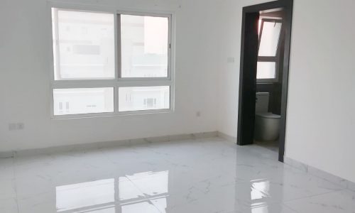 A white tiled room with a window and a door.