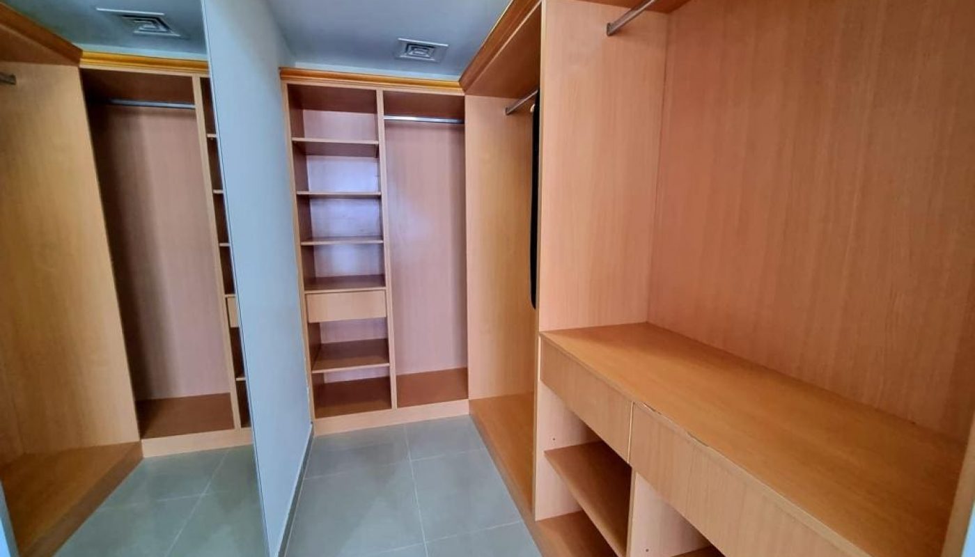 Immaculate closet with wooden shelves and a mirror.