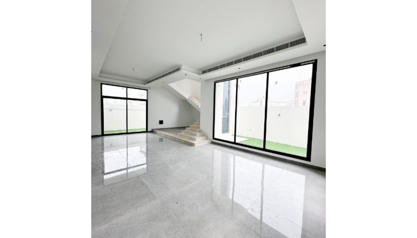 Spacious empty room with large windows, white walls, and a marble staircase leading to an upper floor.