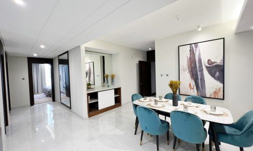 A Fancy Apartment for Sale in Amwaj Islands with blue chairs and a painting on the wall.